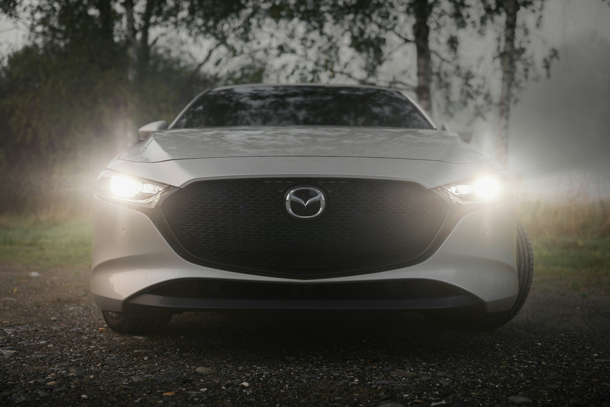 Mazda 3 blanco con las luces encendidas