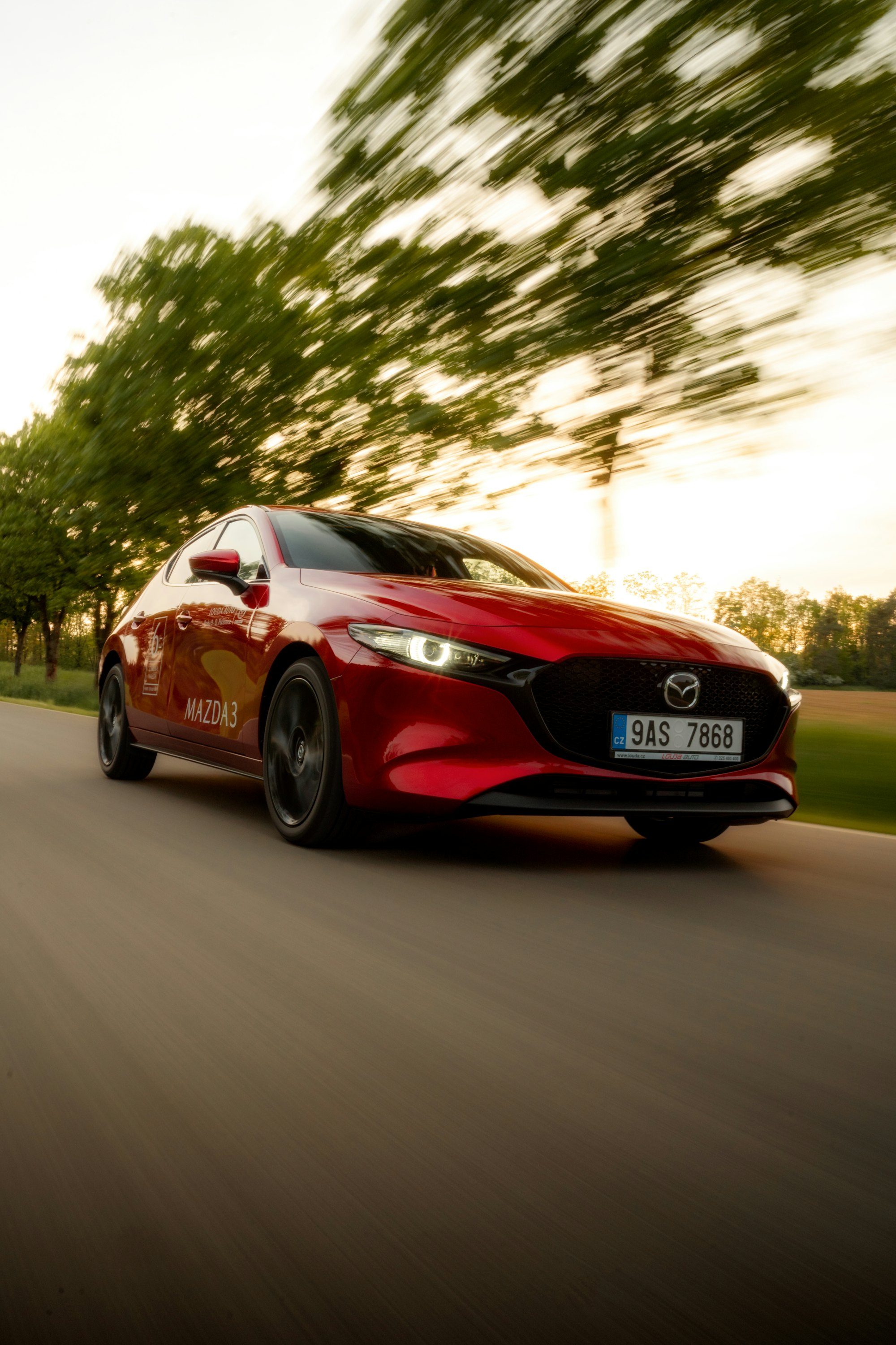 Mazda 3 rojo en movimiento por una carretera