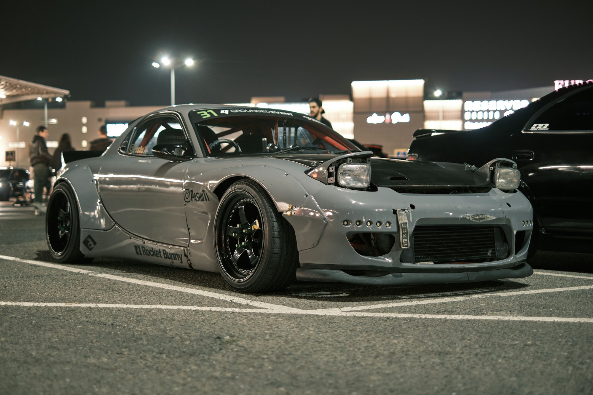 Mazda RX-7 gris en un parqueadero de noche