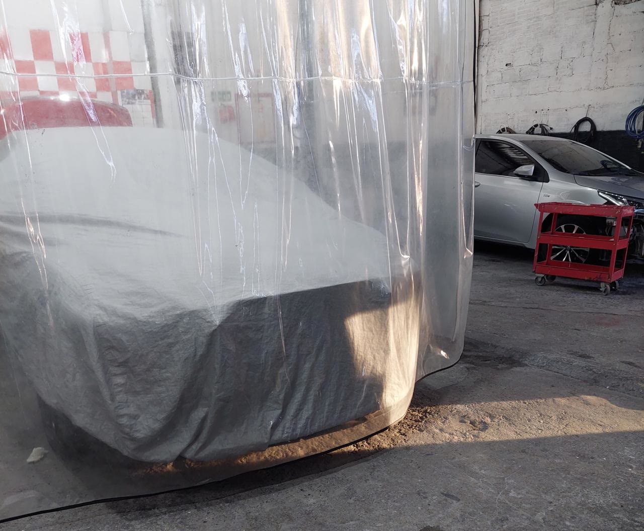 Carro cubierto dentro de la cabina de plástico, listo para pintura