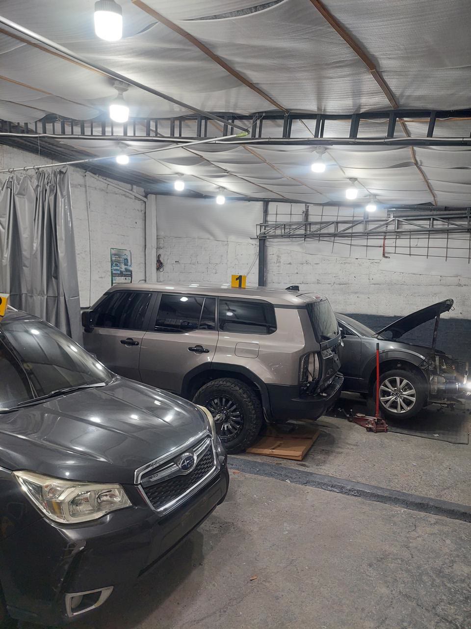 Interior del taller con luces de techo y varios carros en reparación