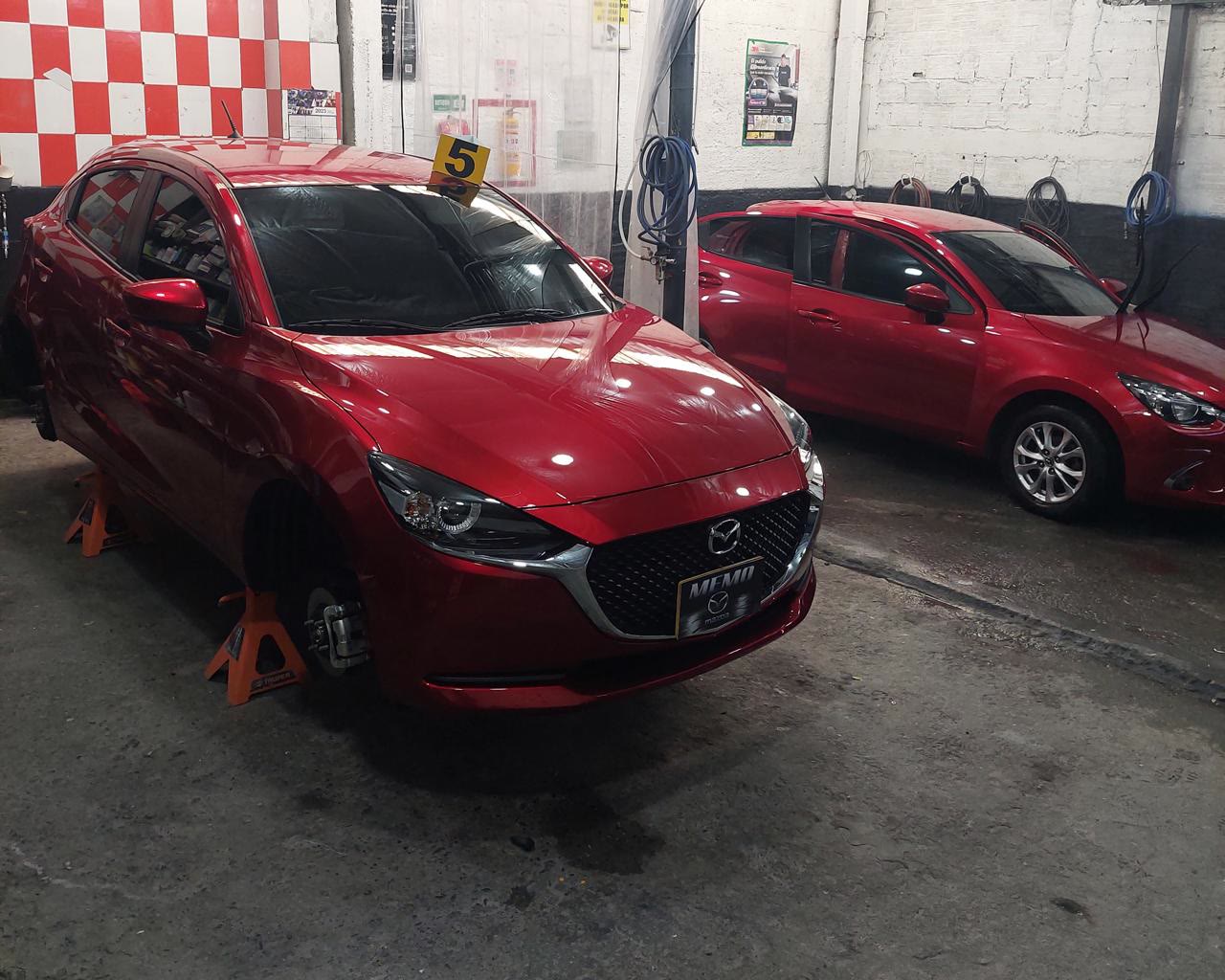 Dos Mazda rojos numerados en turno dentro del taller Memo-Mazda